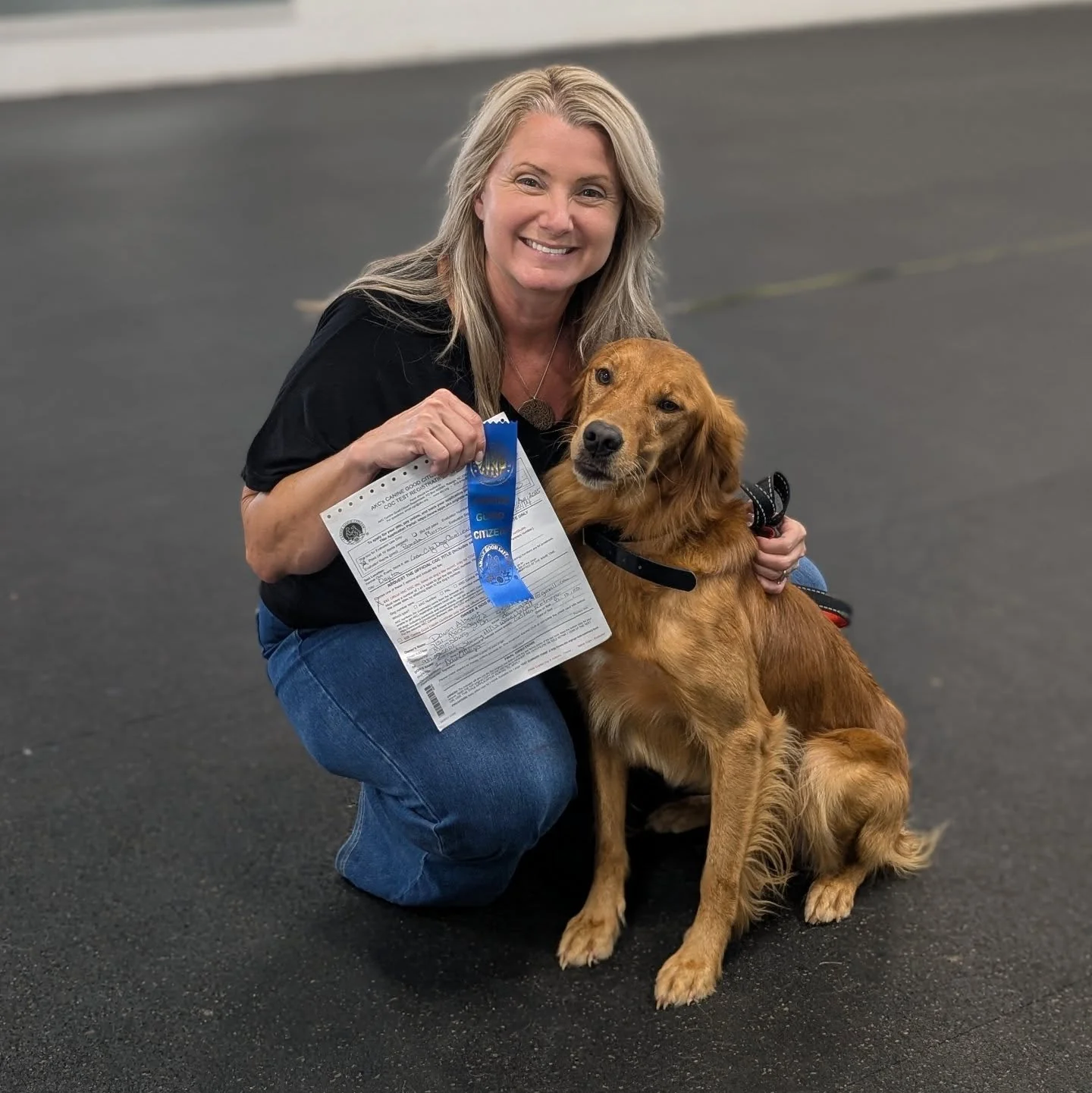 Red golden retriever sitting next to its breeder holding a Canine Good Citizen blue ribbon at Stormy Hill Golden Retrievers in Miamisburg Ohio